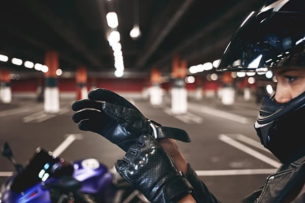 Vrouw met motorhelm aan die handschoen aandoet voor haar motor