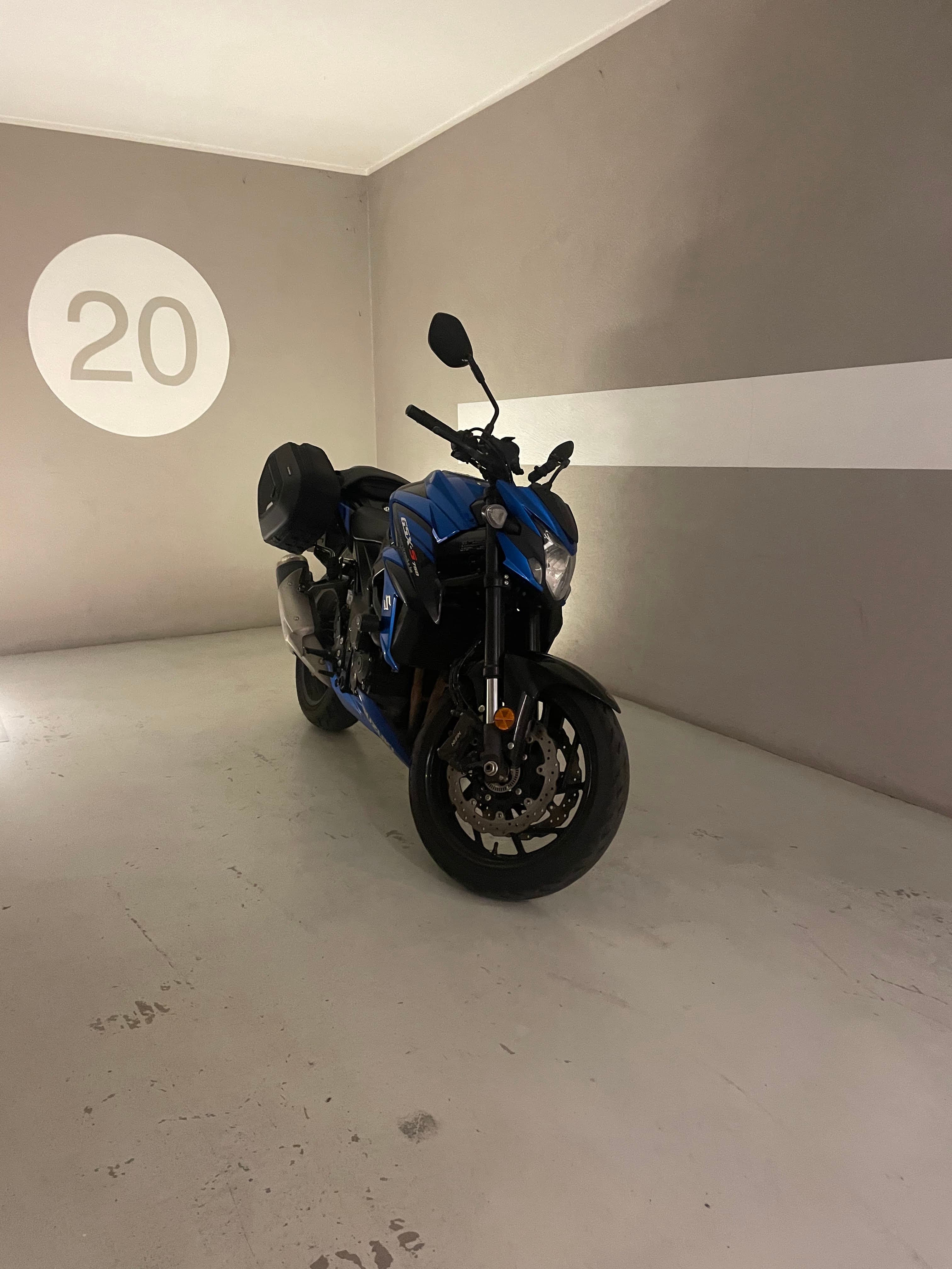 Motor geparkeerd in een ondergrondse privébox met een groot verlicht nummer in Bormio